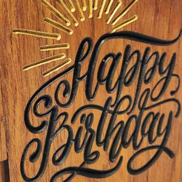 Happy Birthday detail on a wooden greetings card.